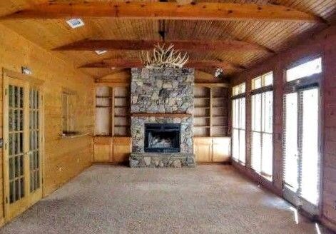 unfurnished living room featuring beam ceiling, a stone fireplace, carpet floors, and wood ceiling