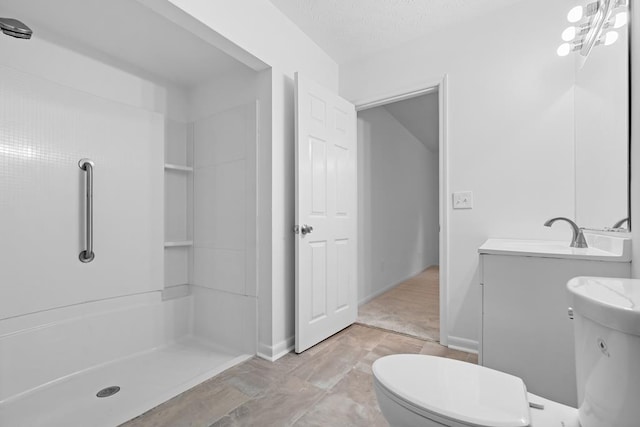 bathroom with a textured ceiling, vanity, toilet, and walk in shower