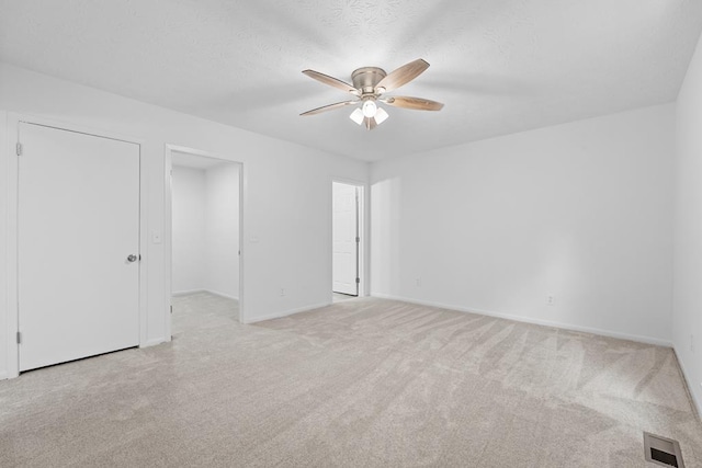 unfurnished room with ceiling fan, light colored carpet, and a textured ceiling