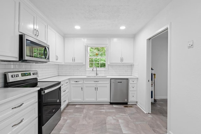 kitchen with a textured ceiling, sink, white cabinetry, and stainless steel appliances