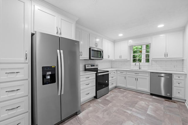 kitchen with stainless steel appliances, white cabinetry, tasteful backsplash, and sink