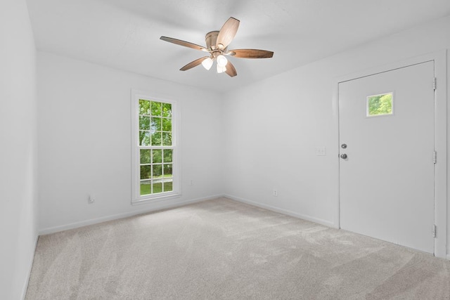 spare room featuring light colored carpet, ceiling fan, and a healthy amount of sunlight