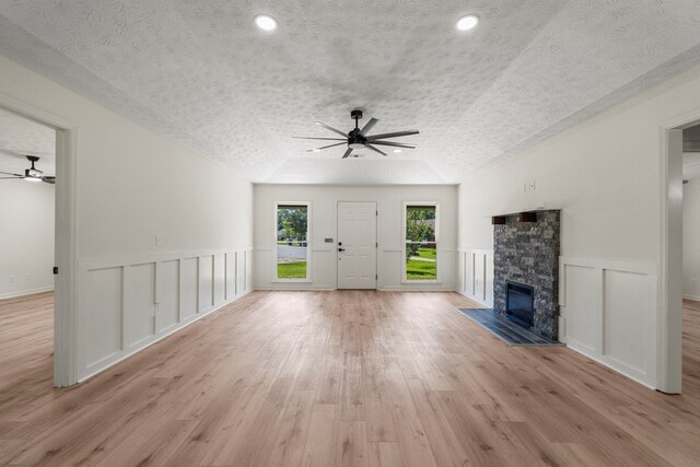 766 Lee Road 0553, Phenix City, AL 36870 - unfurnished living room with a ceiling fan, a fireplace, a textured ceiling, light wood-style flooring, and wainscoting