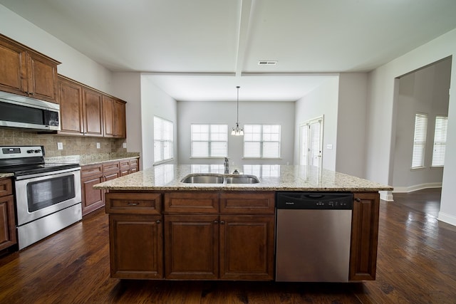 kitchen featuring sink, dark wood-type flooring, an inviting chandelier, a center island with sink, and appliances with stainless steel finishes