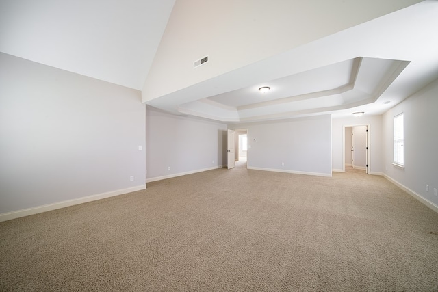 carpeted spare room featuring a tray ceiling