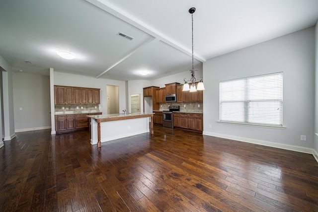 kitchen with pendant lighting, a center island, backsplash, appliances with stainless steel finishes, and a kitchen bar