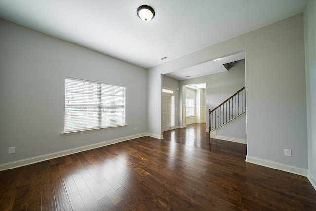 empty room with dark hardwood / wood-style flooring and decorative columns