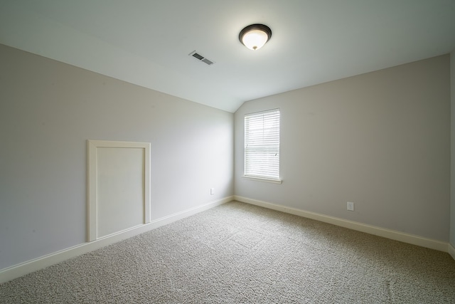 spare room with carpet floors and vaulted ceiling