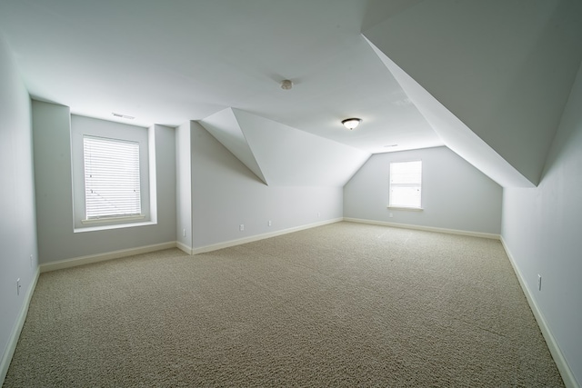 bonus room with plenty of natural light, light colored carpet, and vaulted ceiling