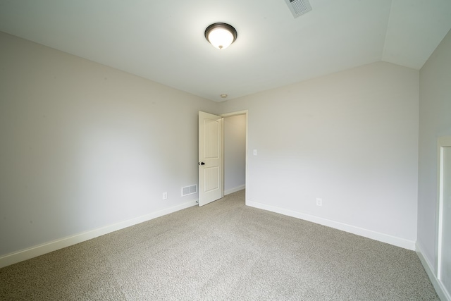 carpeted empty room featuring vaulted ceiling