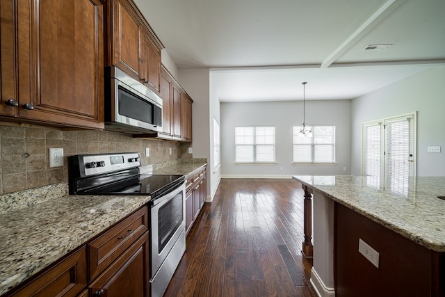 kitchen featuring light stone counters, stainless steel appliances, dark wood-type flooring, a notable chandelier, and hanging light fixtures