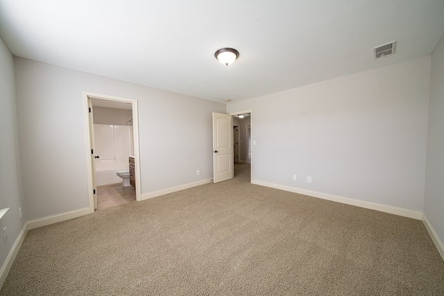 unfurnished bedroom with ensuite bathroom and carpet floors