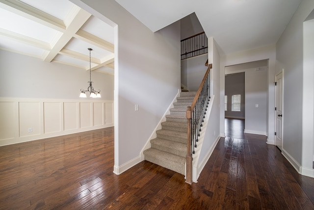 stairs featuring a chandelier, wood-type flooring, coffered ceiling, and beam ceiling