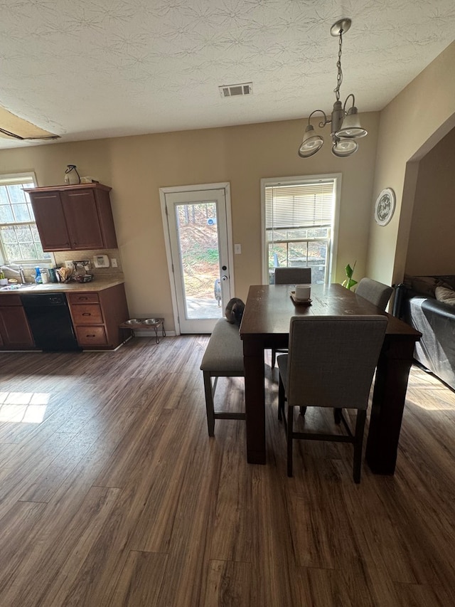 dining room with visible vents, dark wood-type flooring, a chandelier, and a textured ceiling