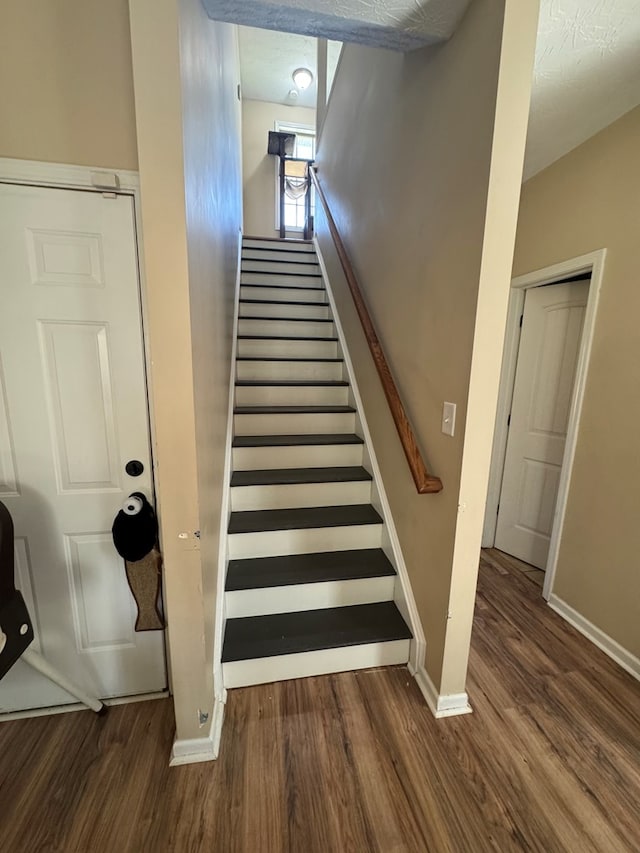 staircase featuring wood finished floors and baseboards