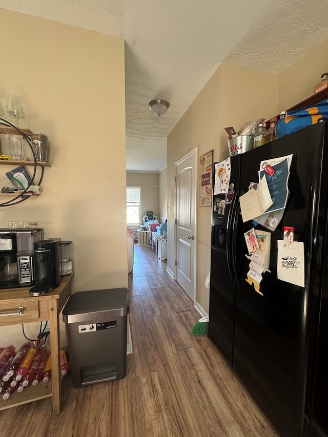 hall with wood finished floors, baseboards, and a textured ceiling