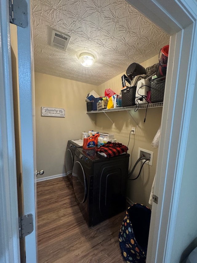 washroom with wood finished floors, baseboards, visible vents, laundry area, and washer and clothes dryer