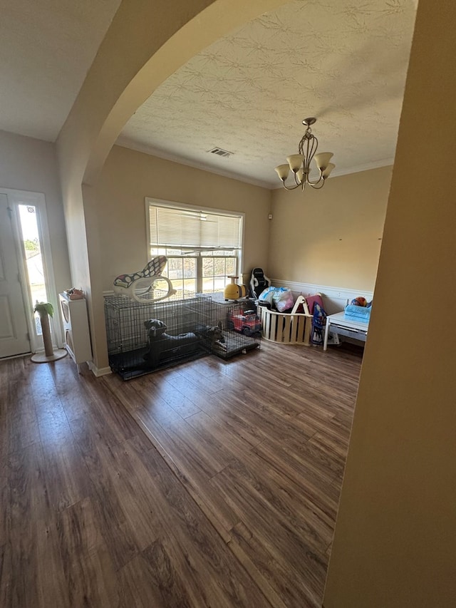 interior space with arched walkways, visible vents, a wealth of natural light, and wood finished floors