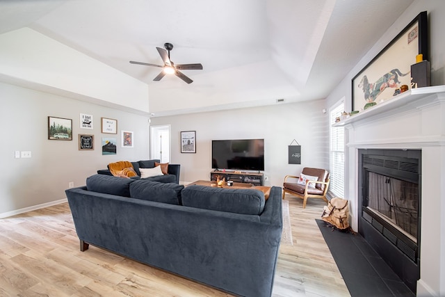 5082 Aaron Ln, Columbus, GA 31907 - living area featuring light wood-style flooring, a ceiling fan, a fireplace with flush hearth, lofted ceiling, and a tray ceiling
