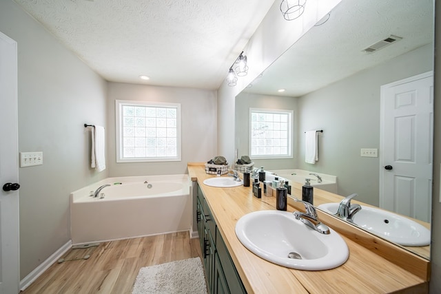 5082 Aaron Ln, Columbus, GA 31907 - bathroom featuring wood finished floors, a bath, double vanity, a textured ceiling, and recessed lighting