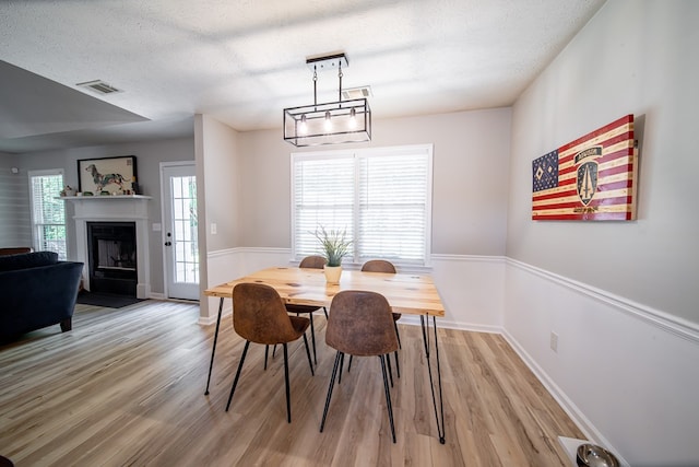 5082 Aaron Ln, Columbus, GA 31907 - dining area featuring light wood finished floors, a textured ceiling, and a fireplace with flush hearth