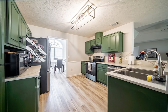 5082 Aaron Ln, Columbus, GA 31907 - kitchen featuring appliances with stainless steel finishes, green cabinets, under cabinet range hood, light wood finished floors, and light countertops