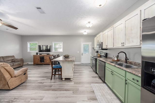 170 Slappy Dr, Hamilton, GA 31811 - kitchen with green cabinetry, stainless steel appliances, open floor plan, a kitchen bar, and a ceiling fan