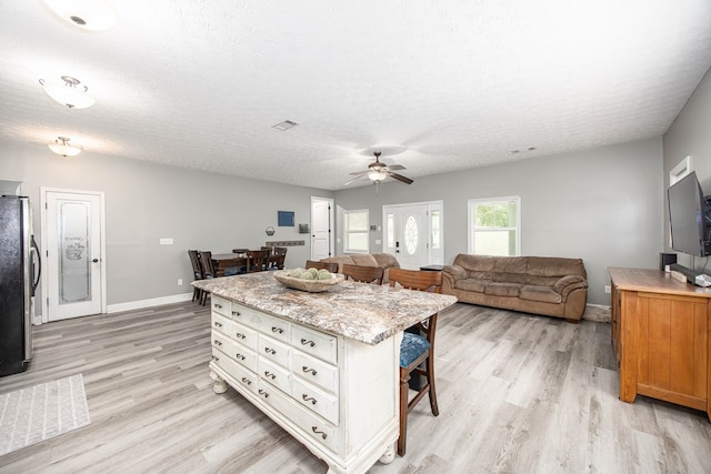 170 Slappy Dr, Hamilton, GA 31811 - kitchen featuring a breakfast bar area, light wood finished floors, freestanding refrigerator, ceiling fan, and a textured ceiling