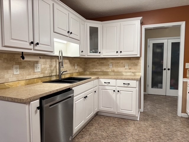 kitchen featuring a sink, dishwasher, white cabinets, and light countertops