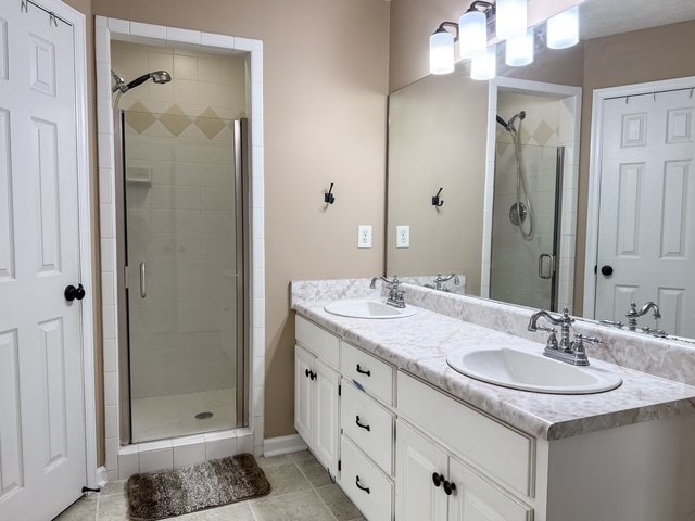 bathroom with tile patterned floors, a stall shower, double vanity, and a sink