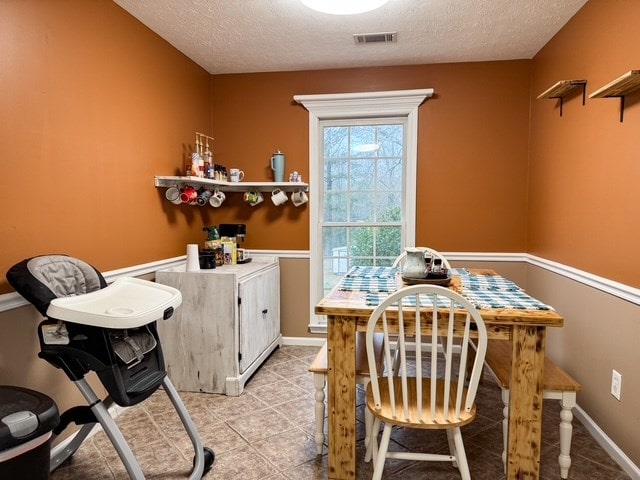 dining area featuring visible vents, baseboards, and a textured ceiling