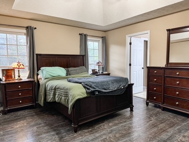 bedroom with dark wood-type flooring and a tray ceiling