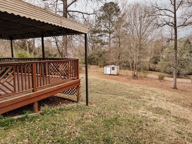 view of yard featuring a deck, a storage shed, and an outbuilding