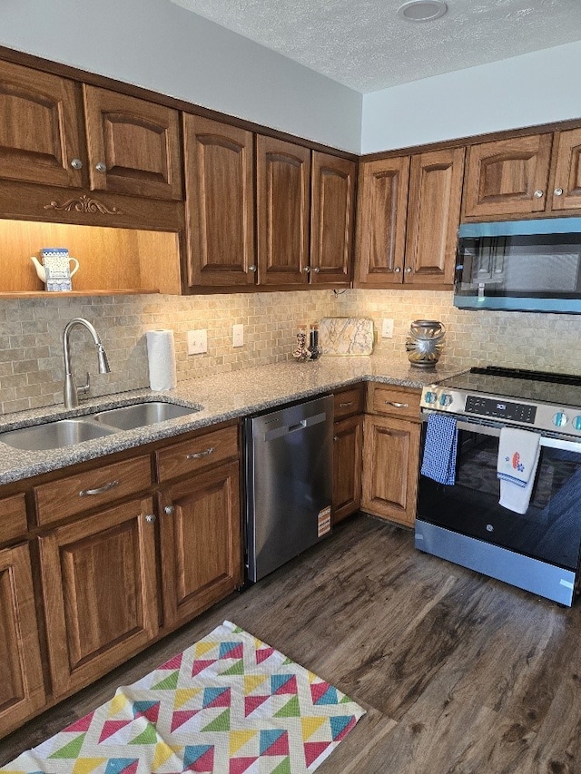 4044 Castlewood Pkwy, Columbus, GA 31907 - kitchen featuring stainless steel appliances, a sink, dark wood-type flooring, light stone countertops, and a textured ceiling