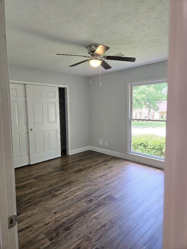 4044 Castlewood Pkwy, Columbus, GA 31907 - unfurnished bedroom featuring dark wood-style flooring, a textured ceiling, a closet, baseboards, and a ceiling fan