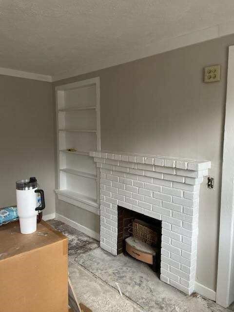 1800 18th Ct, Phenix City, AL 36867 - unfurnished living room with baseboards, ornamental molding, a fireplace, and a textured ceiling