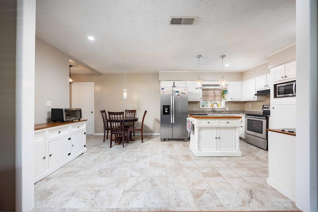 kitchen featuring appliances with stainless steel finishes, sink, a center island, white cabinetry, and hanging light fixtures