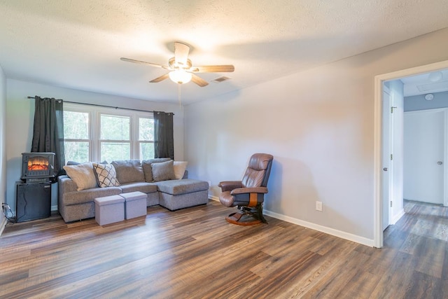 living room with a textured ceiling, ceiling fan, and dark hardwood / wood-style floors