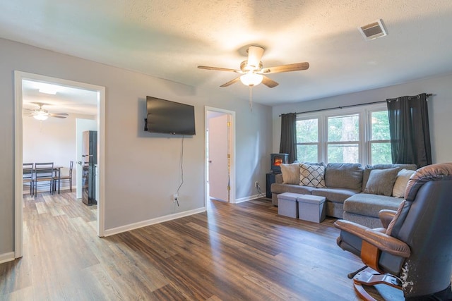 living room with a textured ceiling, hardwood / wood-style flooring, and ceiling fan