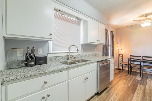 kitchen with white cabinetry, sink, light stone counters, stainless steel dishwasher, and light wood-type flooring