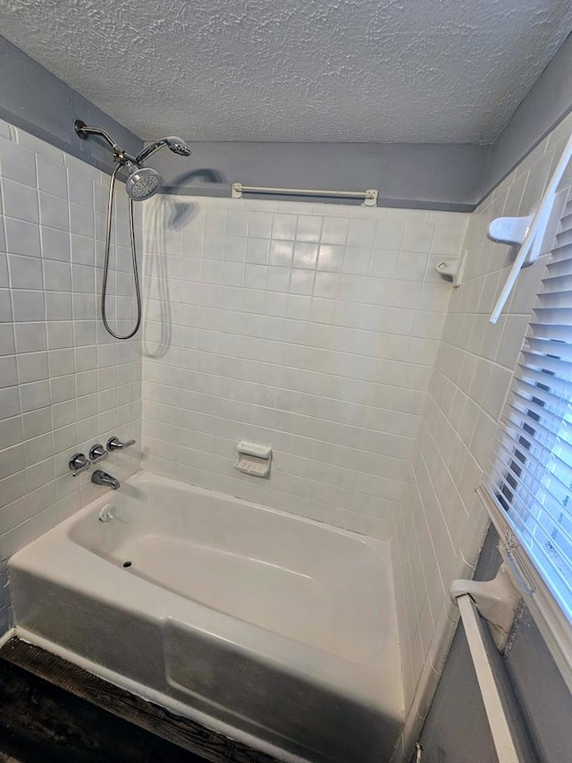 bathroom featuring a textured ceiling and tiled shower / bath