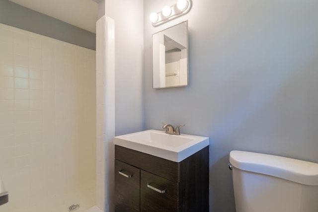 bathroom featuring vanity, toilet, and a tile shower