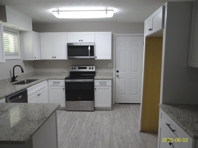 1520 Barcelona Dr, Columbus, GA 31907 - kitchen featuring stainless steel appliances, light stone countertops, light wood-type flooring, and white cabinets