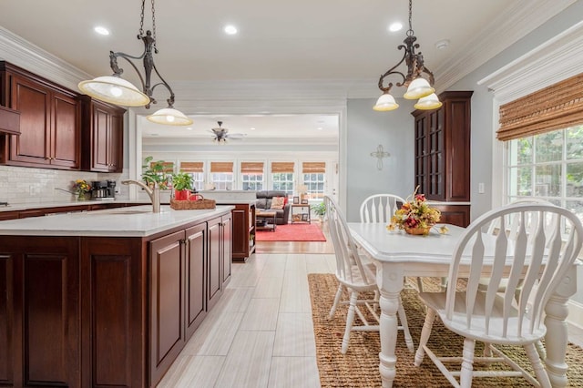 kitchen featuring decorative backsplash, crown molding, plenty of natural light, and hanging light fixtures