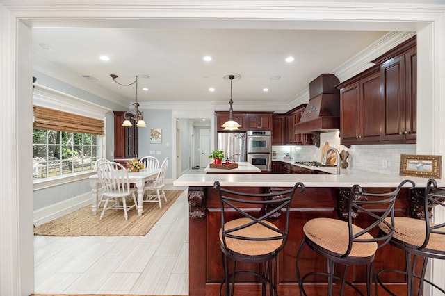 kitchen featuring tasteful backsplash, decorative light fixtures, premium range hood, and stainless steel appliances