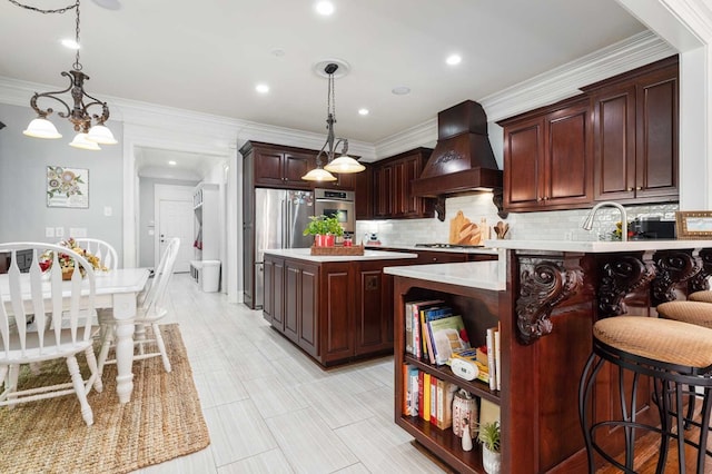 kitchen with custom exhaust hood, ornamental molding, a notable chandelier, a kitchen island, and stainless steel appliances