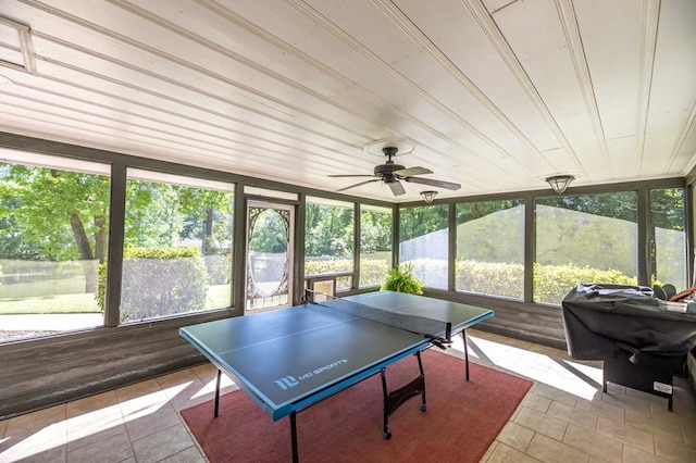 game room with ceiling fan, a healthy amount of sunlight, and wood walls