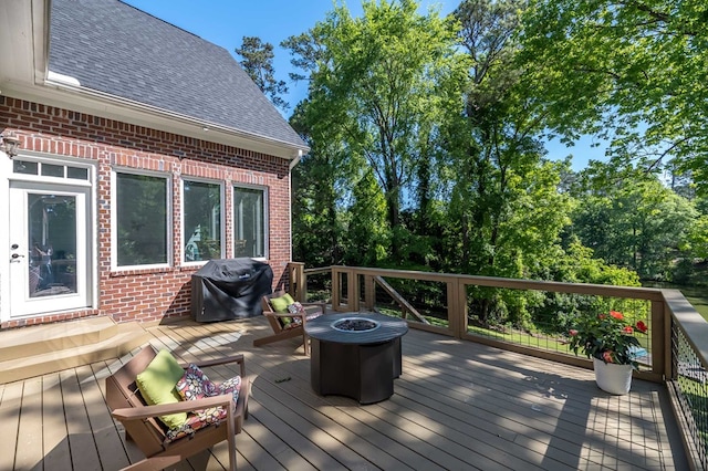 wooden terrace featuring area for grilling and a fire pit