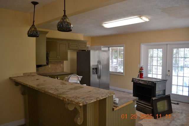 kitchen featuring kitchen peninsula, decorative light fixtures, tasteful backsplash, stainless steel fridge, and green cabinetry