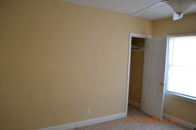 unfurnished bedroom featuring ceiling fan, a closet, light carpet, and a textured ceiling